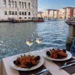 Découvrez un dîner de luxe au bord des canaux de Venise avec des fruits de mer et du vin blanc.