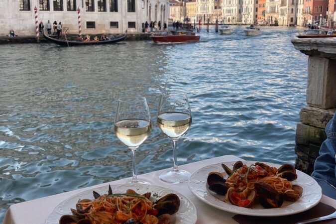 Découvrez un dîner de luxe au bord des canaux de Venise avec des fruits de mer et du vin blanc.