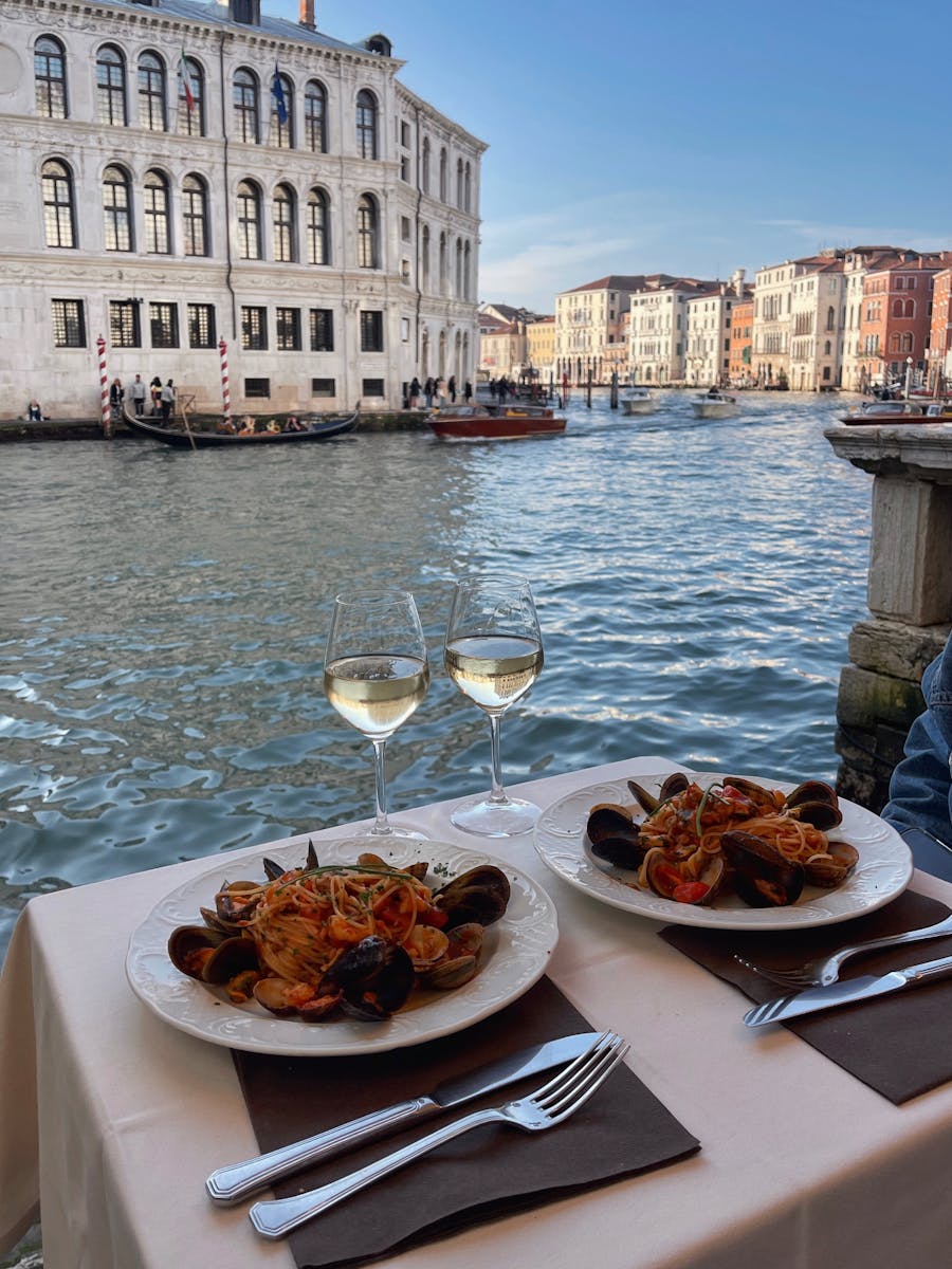 Découvrez un dîner de luxe au bord des canaux de Venise avec des fruits de mer et du vin blanc.