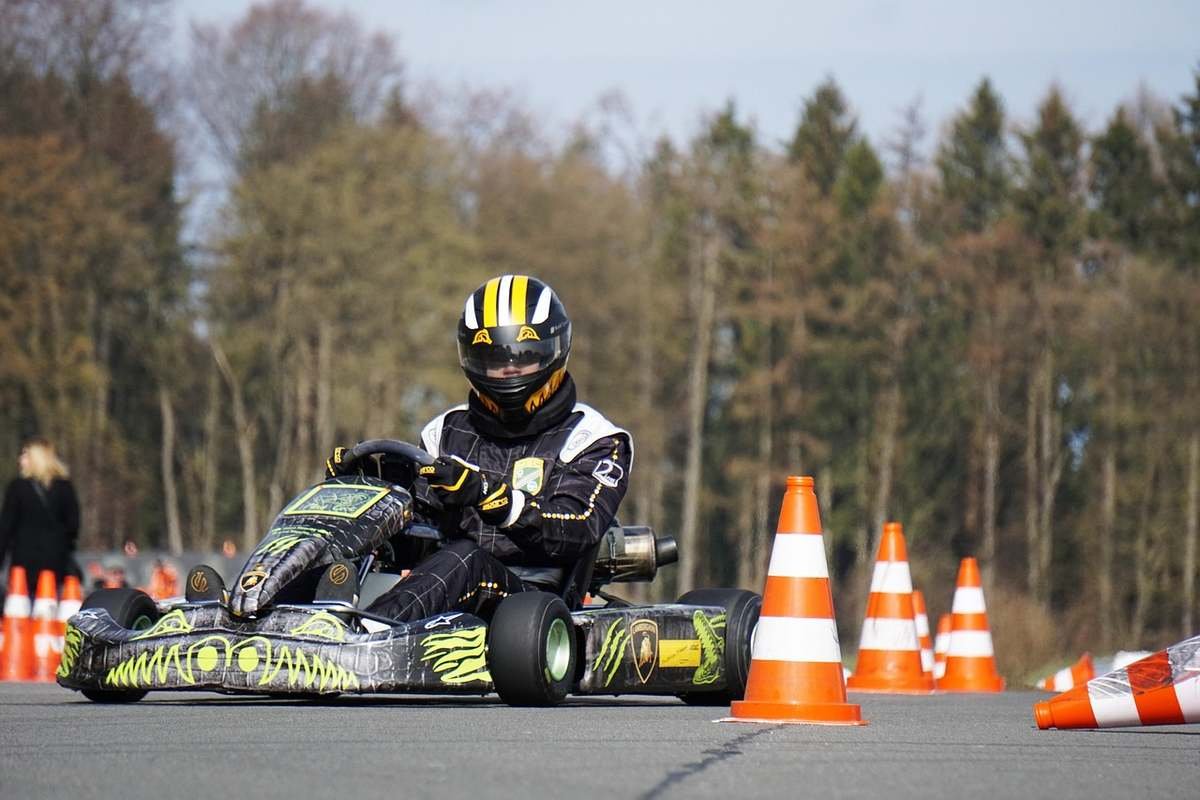 Pilote de kart en action sur un circuit entouré de cônes et de forêt