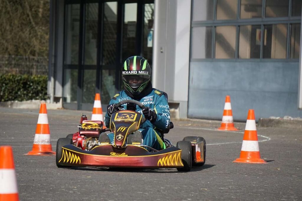 Pilote de kart bleu navigant entre des cônes sur une piste devant un bâtiment