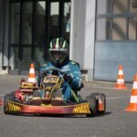 Pilote de kart bleu navigant entre des cônes sur une piste devant un bâtiment