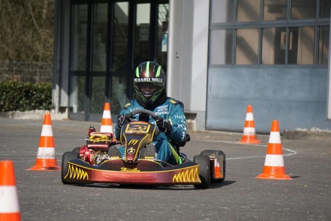 Pilote de kart bleu navigant entre des cônes sur une piste devant un bâtiment