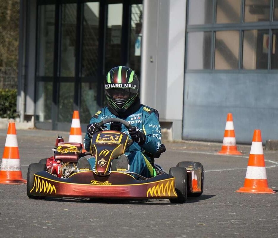 Pilote de kart bleu navigant entre des cônes sur une piste devant un bâtiment