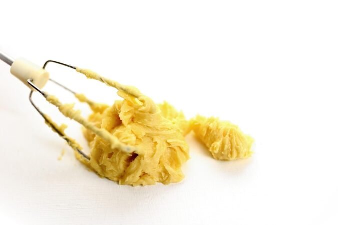 Pâte jaune collée aux fils du fouet sur fond blanc