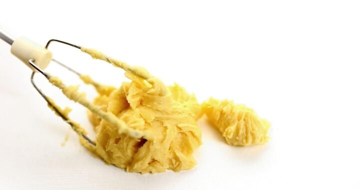Pâte jaune collée aux fils du fouet sur fond blanc