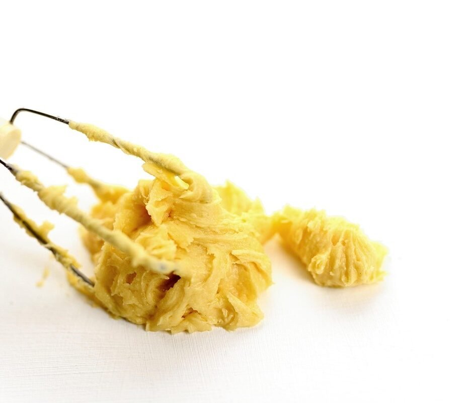 Pâte jaune collée aux fils du fouet sur fond blanc