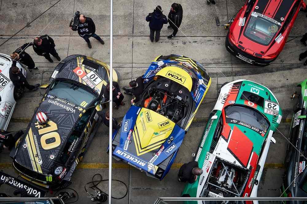 Des voitures de sport et leurs équipes travaillent dans le stand pit