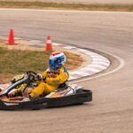 Un coureur en combinaison jaune pilote un kart sur virage de circuit
