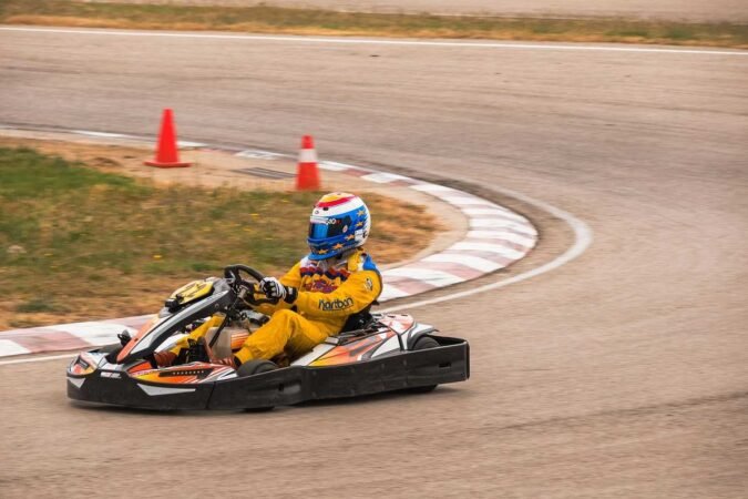 Un coureur en combinaison jaune pilote un kart sur virage de circuit
