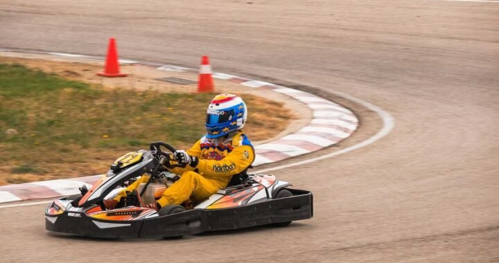 Un coureur en combinaison jaune pilote un kart sur virage de circuit
