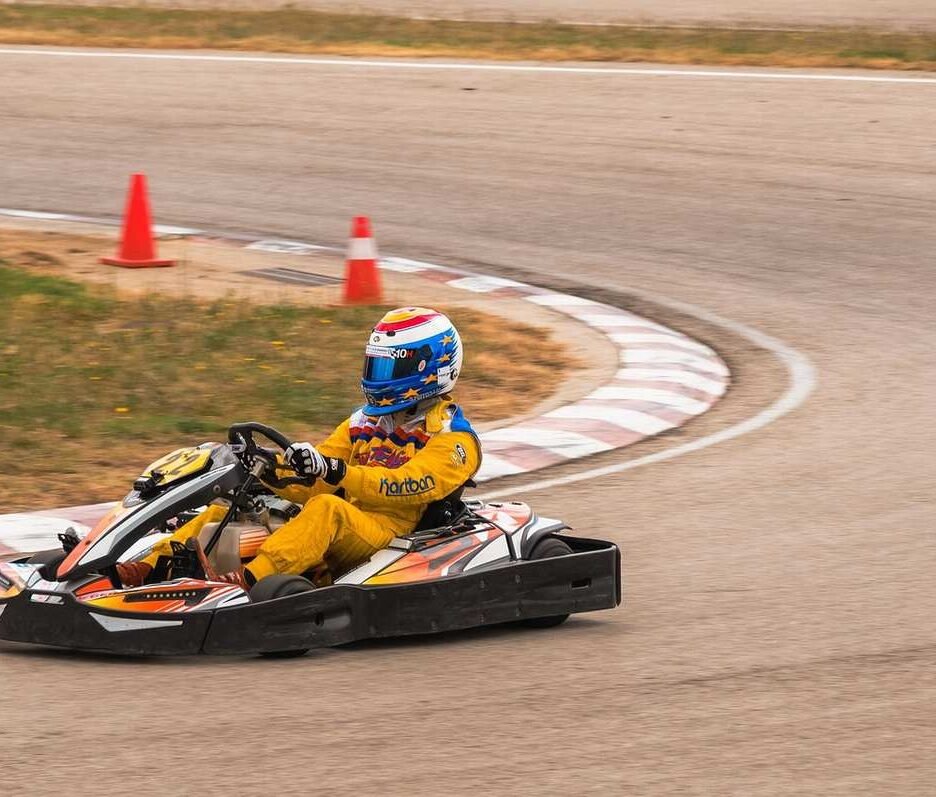 Un coureur en combinaison jaune pilote un kart sur virage de circuit
