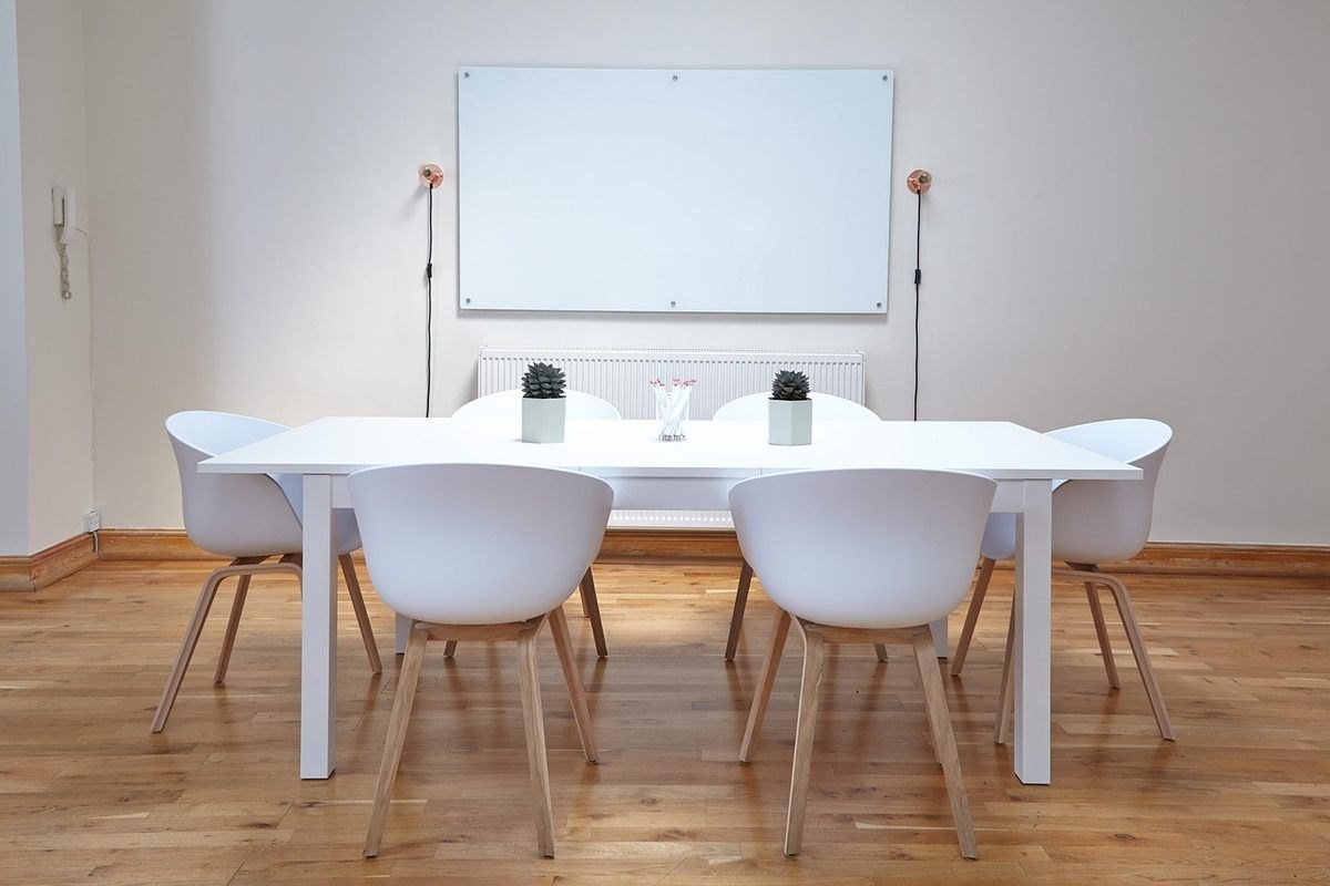 Une salle minimaliste avec table chaises tableau blanc et deux vases