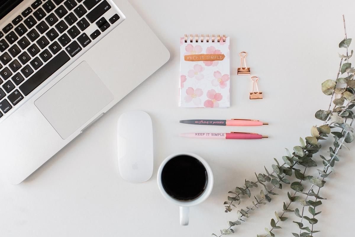 Bureau avec ordinateur, café, stylos, papier et plantes